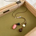 Close-up of a new Chinese style acorn pendant necklace with a Zen style brown woven cord - Pink Acorn Double Pendant Style