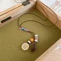 Close-up of a Zen-style acorn pendant necklace with a wood slice and beads displayed in a wooden box - Blessing Bead Acorn Style