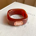 Macro view of a brown resin bangle with a large peach faceted gemstone on a textured book page - Brown