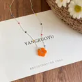 Close-up of a colorful beaded necklace with a vibrant orange flower pendant. - Silver/Orange