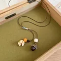 Close-up of vintage acorn pendant necklace with woven cord inside a wooden jewelry box. - Yellow Petal Acorn Style