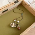 Close-up of Zen style necklace featuring a realistic acorn and dried citrus slice pendant. - Dried Orange Slice Acorn Style