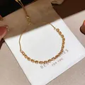 Close-up detail of a shiny gold-plated zircon flower bracelet on a white gift bag - Style 10 Bracelet