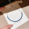 Detail of a sparkling silver bracelet with teardrop blue zircons on a white gift pouch - Style 11 Bracelet
