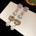 Close-up of elegant square crystal and pearl drop tassel earrings on a display box - Silver