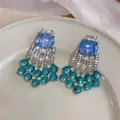 Close-up of vintage palace style earrings with blue resin and green bead tassels. - Blue / 925 Silver Needle / Silver