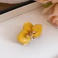 Dettaglio macro dell'orecchino a fiore giallo con petali in smalto a goccia marmorizzato - Anello / Oro Ecologico / Giallo