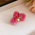 Dettaglio macro di orecchino a fiore di orchidea in smalto rosa e metallo dorato - Anello / Oro Ecologico / Rosa