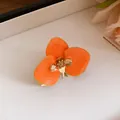 Primo piano di un raffinato orecchino a lobo vintage a fiore in smalto arancione e oro. - Anello / Oro Ecologico / Arancione