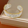 Vista dettagliata di un bracciale a polsino traforato in stile retrò francese bicolore - Argento con Bordo Oro
