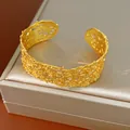 Primo piano di un bracciale rigido dorato stile vintage francese con pizzo traforato - Oro