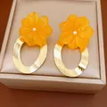 Close-up detail of yellow resin flower earrings with brushed gold-tone oval hoops - Flower Hoop Style / Gold-Yellow