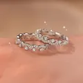 Macro view of two zircon lace rings with sparkling wave design on a soft skin background - Two-Piece Set / Silver