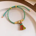 Close-up of hand-woven colorful rope bracelet with clover charm and tassel - Lucky Clover
