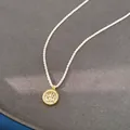 Detailed macro view of a gold north star pendant with zircon on white knotted cord - Octagram Compass Necklace