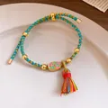 Close-up of a handmade braided multi-colored bracelet with 'Ping An' charm and tassel. - Peace and Joy