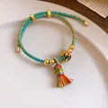 Close-up of handmade braided five-color rope bracelet with colorful tassel detail - Gourd