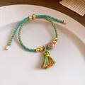 Detailed view of handmade woven five-color rope bracelet with tassel and Fu charm - Russian Doll