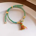 Detail view of handmade braided five-color cord bracelet with a peace charm and tassel - Peace Lock Pendant