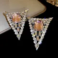 Macro view of triangular pink crystal earrings with sparkling diamond studs - Pink