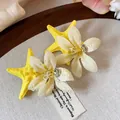 Macro view of starfish and flower hair clip with sparkling water-drop details - Duckbill Hair Clips / Yellow