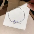 Detail view of a silver flower bracelet with sparkling zircons on a white gift bag - 39# Bracelet