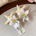Detailed view of exquisite starfish and flower hair clips on a textured background. - Duckbill Hair Clips / White