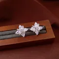 Close-up view of sparkling flower zircon stud earrings on a wooden jewelry display - Clip-On Earrings / One Pair / Silver