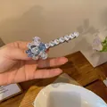 Détail d'une élégante pince à cheveux papillon en zircon avec un petit ours en résine. - Bleu