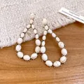 Primo piano di orecchini vintage a goccia con pietre marmoree bianche e cornice dorata - Bianco