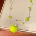 Close-up of double-layered necklace featuring a vibrant green resin apple pendant - Necklace - Silver - Green