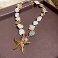 Detailed close-up of a gold starfish pendant necklace featuring iridescent mother-of-pearl beads - Gold-Starfish