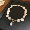 Macro detail of a beach style shell necklace with faux pearl pendant and toggle clasp - Gold-Artificial Pearl