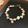 Close-up of beach style choker necklace with irregular shells and gold shell pendant - Gold - Shell