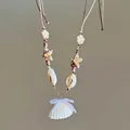 Detail view of beach style necklace featuring natural shells, starfish, and pearls. - White-Coffee