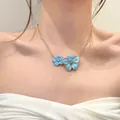 Detailed close-up of a gold chain necklace with two elegant blue enamel flower pendants. - Blue