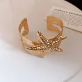 Dettaglio di un bracciale rigido dorato a forma di stella marina con texture martellata - Forma a stella marina / Oro