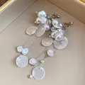 Detalle de pendientes de clip con borlas de perlas barrocas y discos de concha. - Estilo de Clip / Blanco