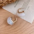 Detail view of retro C-shaped earrings with gold-tone metal and white marble resin finish - Gold-White