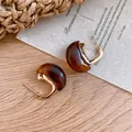Close-up detail of vintage tortoiseshell resin C-shaped hoop earrings with gold finish. - Gold Brown