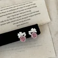Primo piano di orecchini a lobo a fiore rosa con delicati petali bianchi e strass - Rosa
