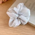 Detailed view of a white polka dot and sheer double-layered fabric hair scrunchie. - Polka Dot / White