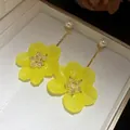 Detailed view of yellow flower drop earrings with pearls and crystal centers in a box - Yellow