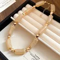 Primo piano di una collana vintage con perle di acrilico beige e distanziali dorati - Beige