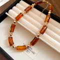 Dettaglio di una collana vintage con perle in acrilico marrone e sfere dorate. - Caffè Scuro