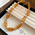 Dettaglio di una collana vintage in perle acriliche ambrate in una scatola portagioie - Caffè Chiaro