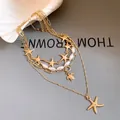 Close-up of a multi-layered gold necklace with pearls, starfish, and a sea turtle pendant. - Multi-layer Starfish Turtle Necklace / Gold