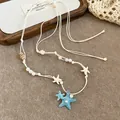 Beach vacation necklace with blue starfish pendant and faux pearls on beige cord - White-Blue
