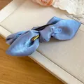 Detailansicht einer blauen Satin-Schleifen-Haarklammer mit goldenem Hasenanhänger. - Blau