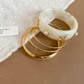 Macro view of a resin bangle with pearl and golden starfish details from the set - Gold, White